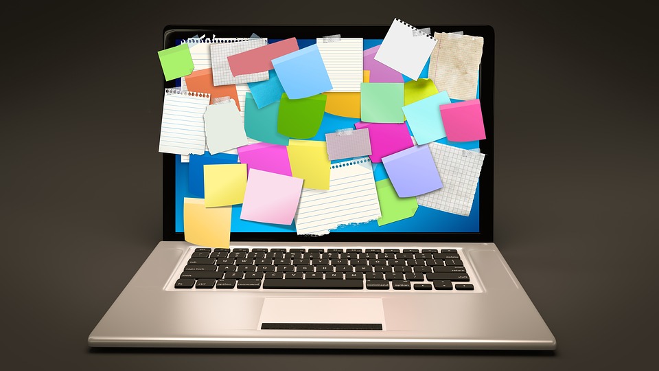 Auf dem Bild ist ein Notebook zu sehen, auf dessen blauen Desktop bunte Post-Its angebracht sind.