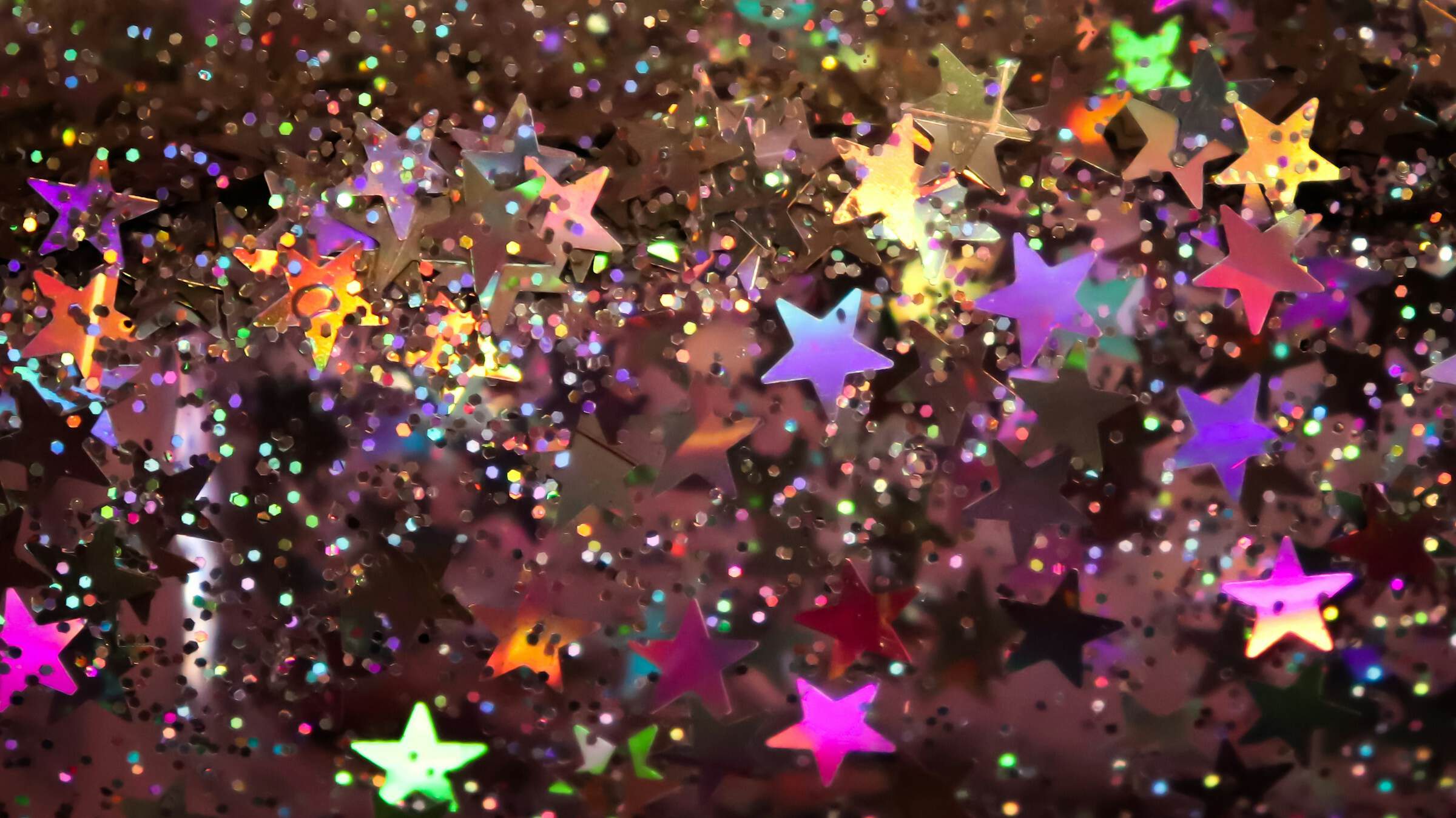 Kleine Silberne Sterne und Konfetti die buntes Licht reflektieren,